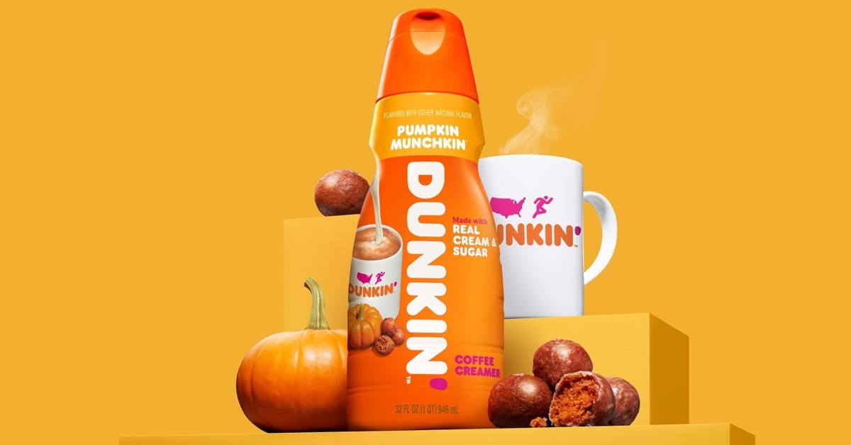 Dunkin’ Pumpkin Munchkin Coffee Creamer surrounded by a pumpkin, munchkins, and a mug of Dunkin' coffee
