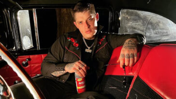 Ryan Upchurch holding a drink bottle and a pair of eyeglasses inside a car