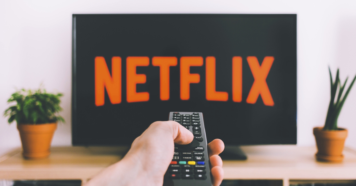Man holding a TV remote control and checking out the 10 best Netflix movies right now