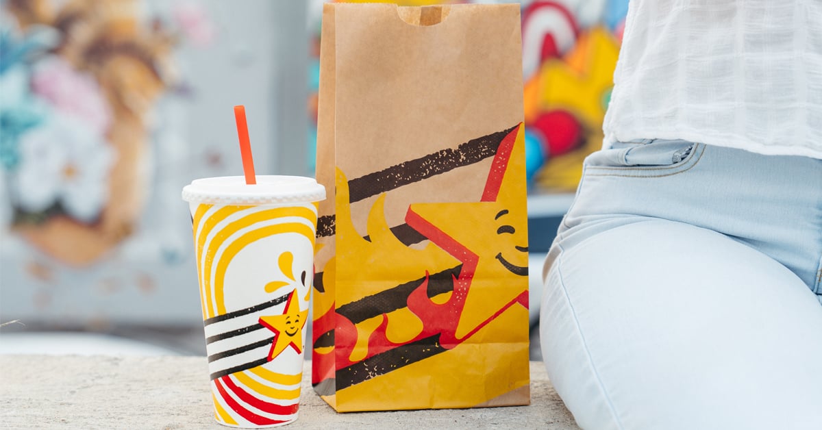 A beverage cup and paper bag featuring Carl's Jr. and Hardee's new brand identity