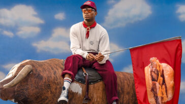 Pusha T riding on a bull while holding a flag with a photo of Arby's new Real Country Style Rib Sandwich
