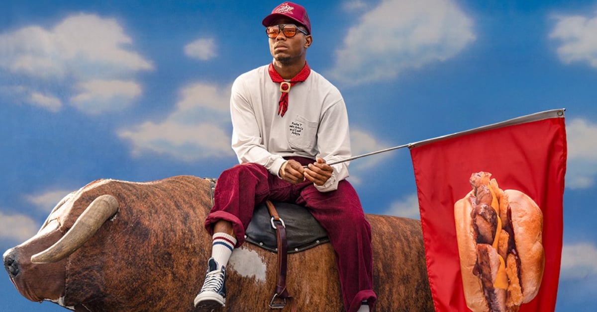Pusha T riding on a bull while holding a flag with a photo of Arby's new Real Country Style Rib Sandwich