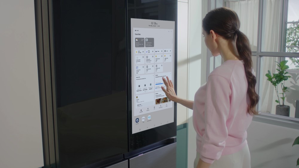 Lifestyle image of woman using display on the Samsung Bespoke 4-Door Flex With Family Hub+ smart refrigerator in a Samsung smart kitchen