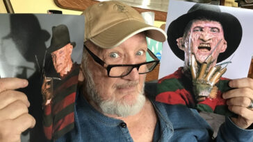 Robert Englund holding Freddy Krueger posters