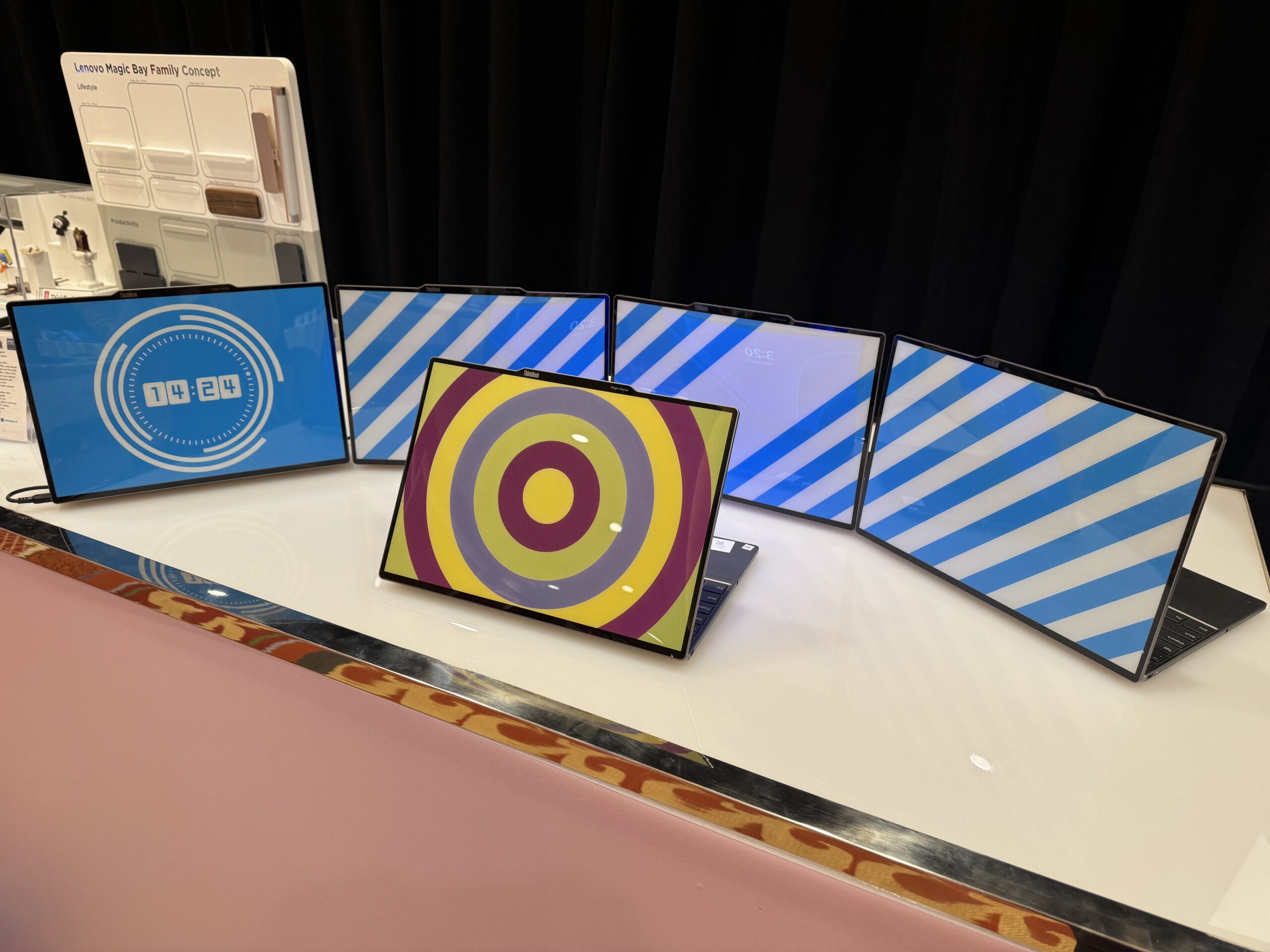 Images of multiple Lenovo ThinkBook 13x Gen 4 SPE on display at CES 2024 showing geometric patterns and a clock on the E Ink displays