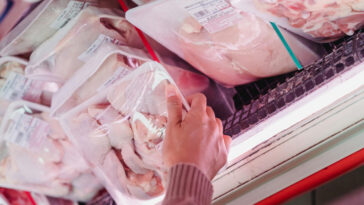 Shopper holding a pack of frozen chicken with labels | ©Image Credit: Kevin Malik/Pexels