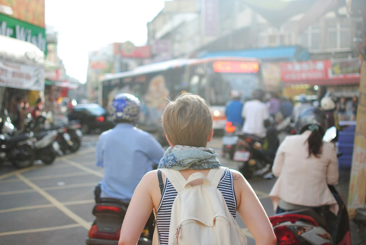 Woman wearing a backpack walking on a road | ©Image Credit: Unsplash / Steven Lewis