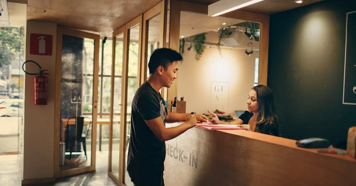 A man standing in front of a hotel front desk | ©Image Credit: Helena Lopes/Pexels