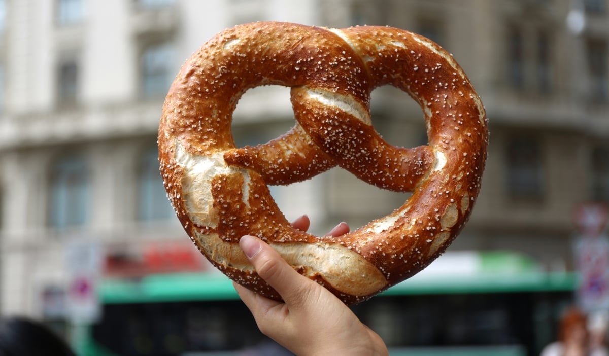 A person holding a soft pretzel in Basel, Switzerland | ©Image Credit: Unsplash / Pierre Gui