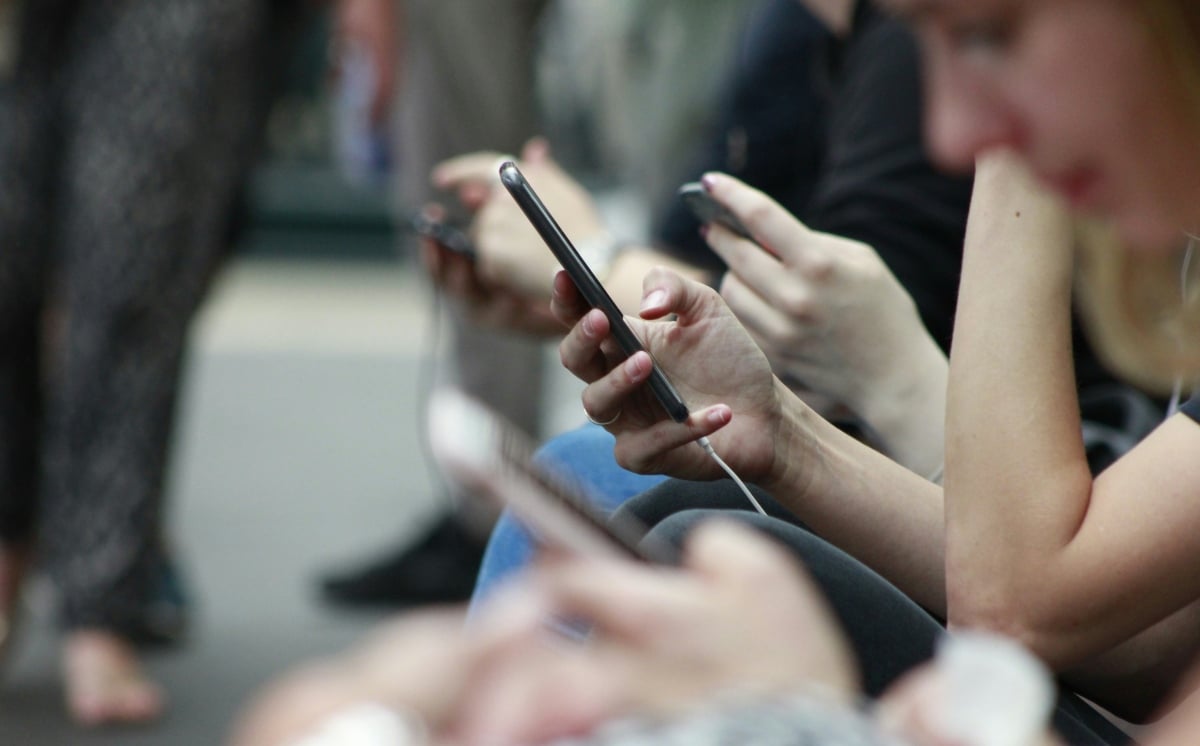 A line of people busy with their phones whilst waiting for a train | ©Image Credit: Unsplash / Robin Worrall