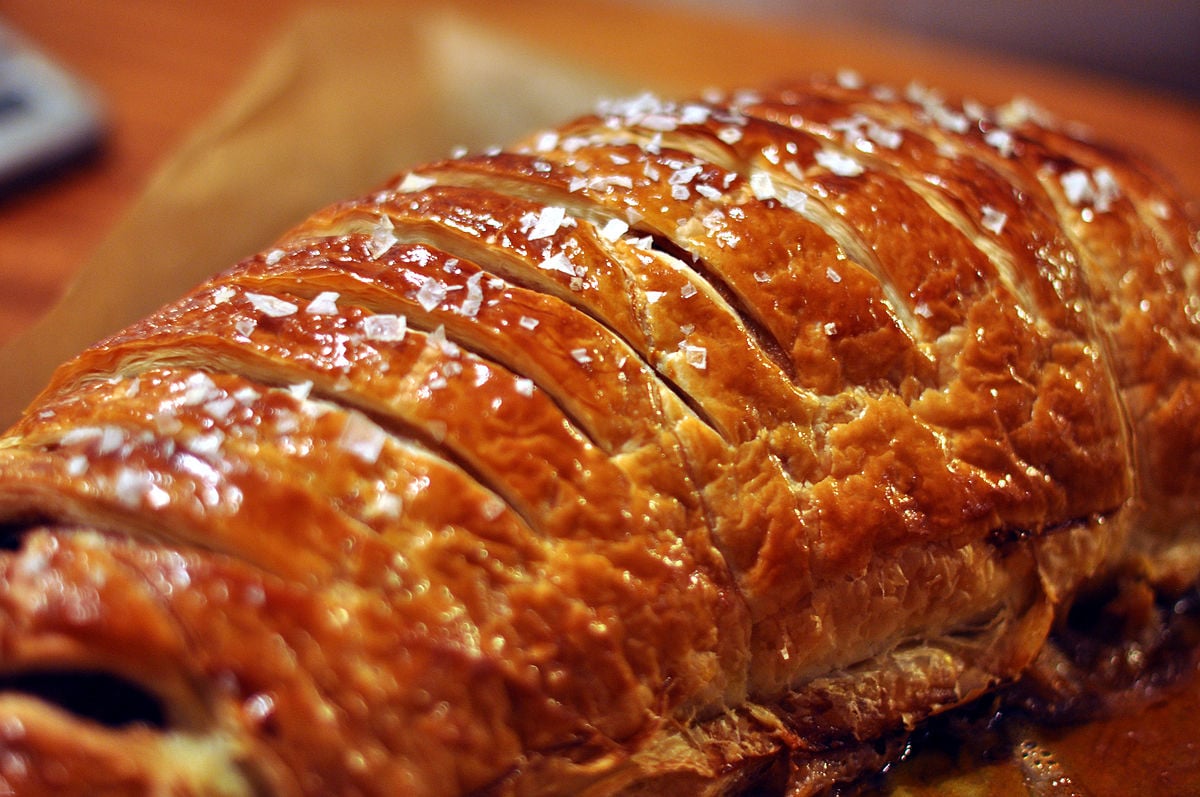 Close-up of a golden-brown Beef Wellington with a glossy pastry crust scored with diagonal cuts | ©Image Credit: Wikimedia Commons / cyclonebill