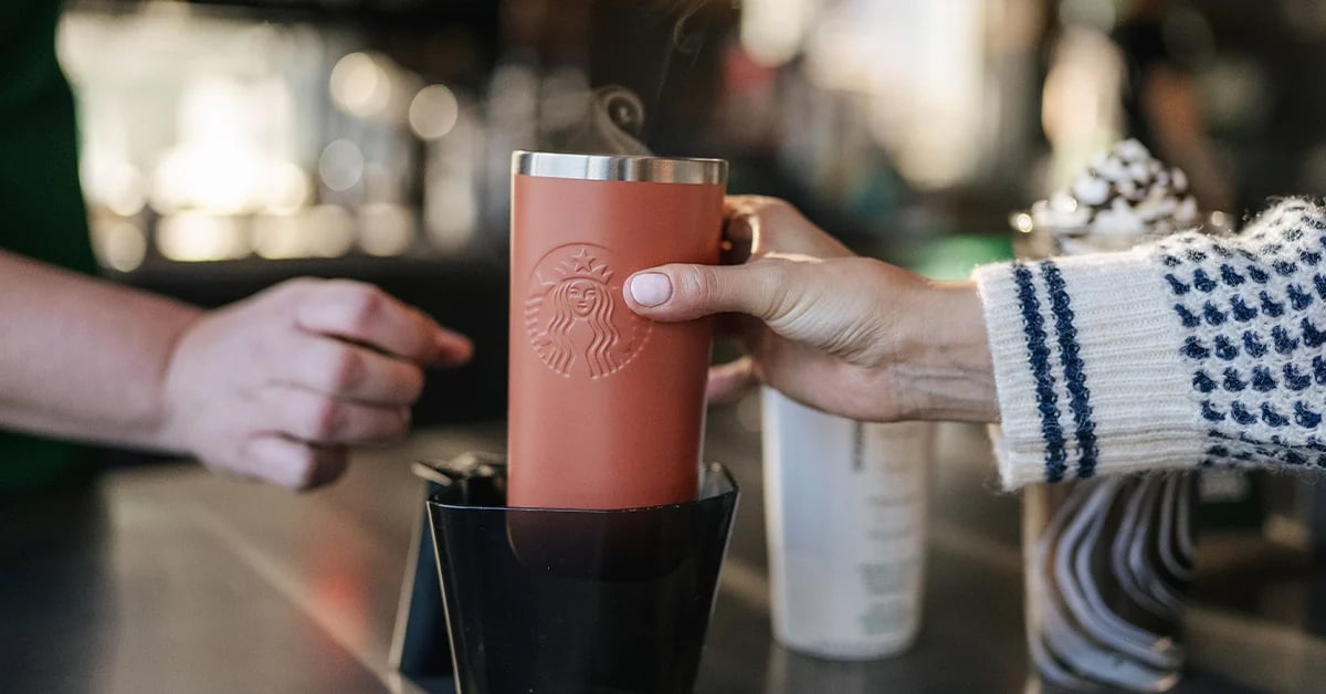 Starbucks staff member serving coffee in a reusable cup brought by a customer | ©Image Credit: Starbucks