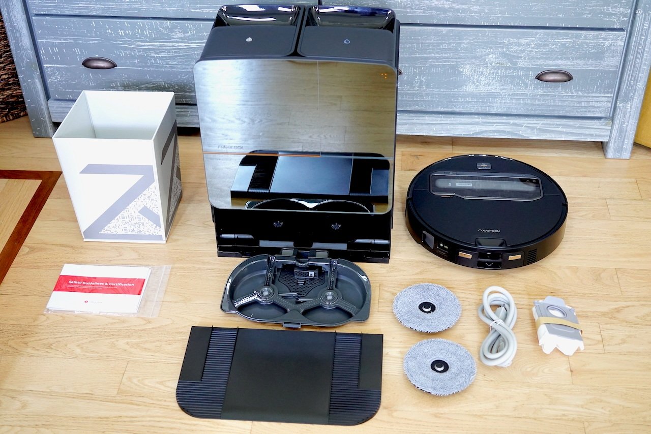 Complete Roborock Saros Z70 system with vacuum, docking station, mop pads, cables and accessories laid out on wooden floor