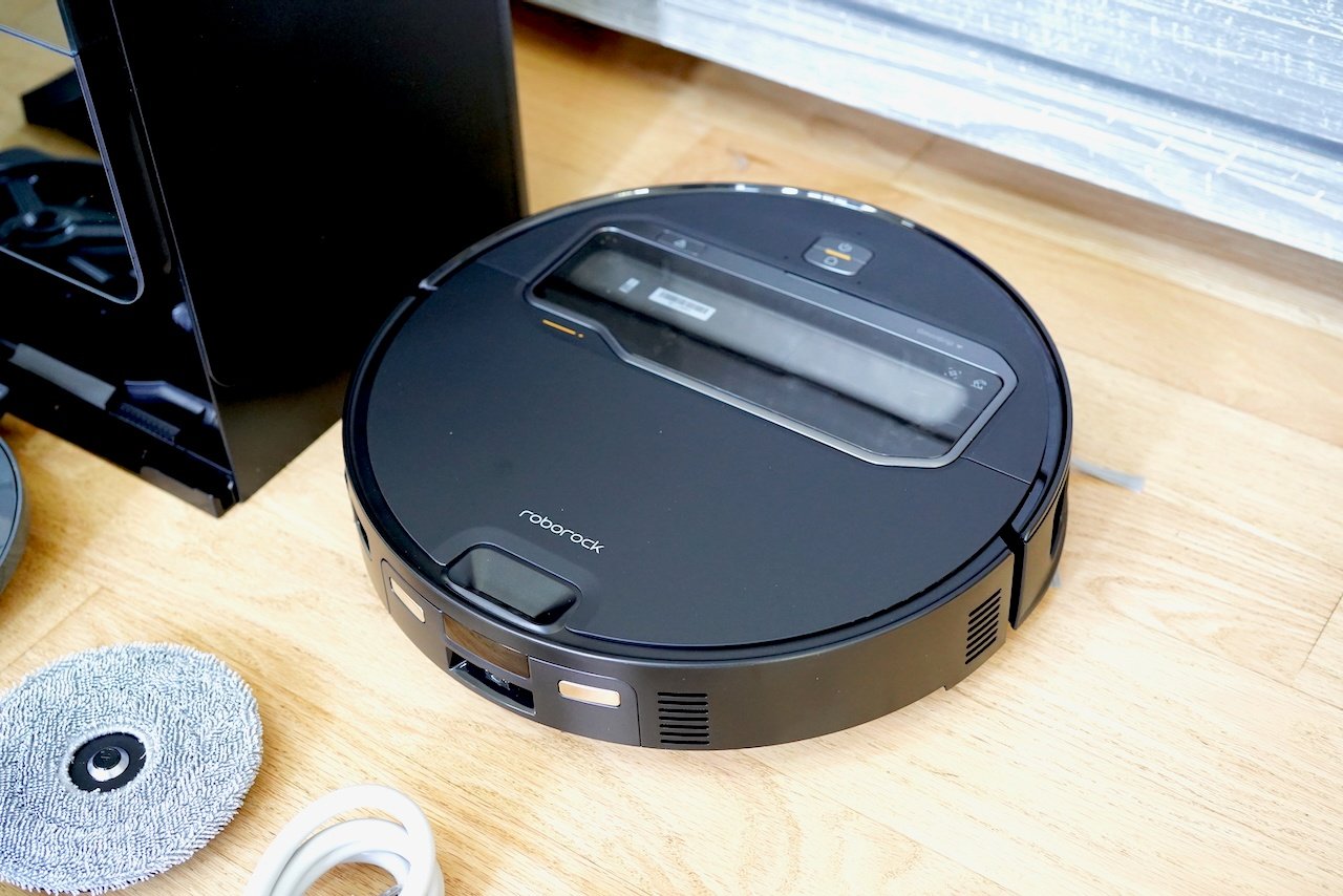 Clean top-down view of black Roborock Saros Z70 with brand name visible, mop pad and cable nearby 