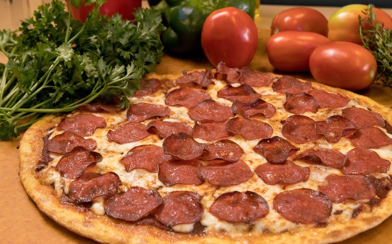8 Ultra-Processed Meats Experts Say to Avoid 7 Pepperoni Pizza placed near some greens and tomatoes