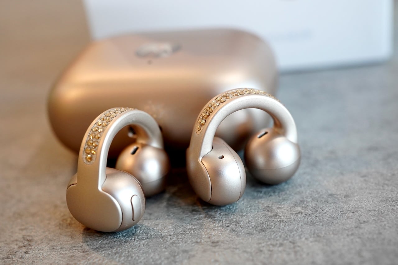 Detailed view of Moto Buds Loop earbuds (with charging case in the background) highlighting crystal embellishments and build quality
