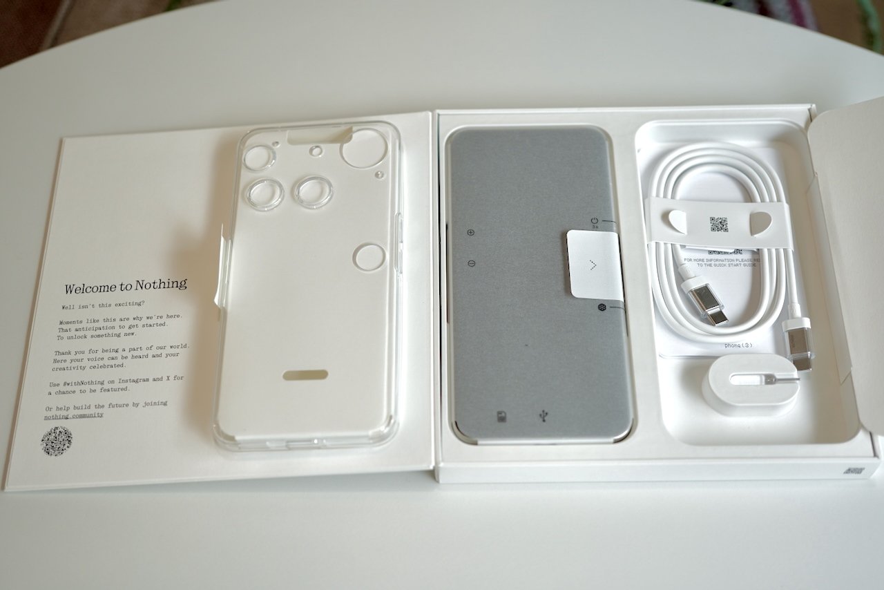 Nothing Phone 3 unboxing showing phone, clear case, cable and Welcome to Nothing packaging