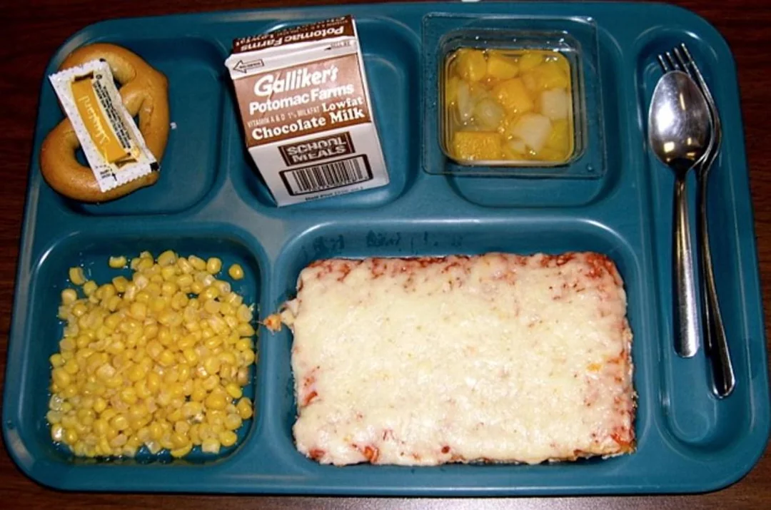 School lunch from the '80s featuring cheese pizza, corn, pretzel with mustard, fruit cocktail, and chocolate milk | ©Image Credit: Reddit / HistoricalCapsule / zadraaa