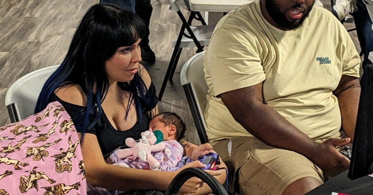 Balancing gaming passion with motherhood, this gamer mom competes while cradling her newborn daughter. | ©Image Credit: @Argenrost/X