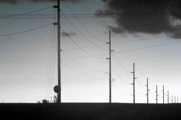 Overhead utility lines stretch along a row of poles | ©Image Credit: Pexels / Tom Fisk