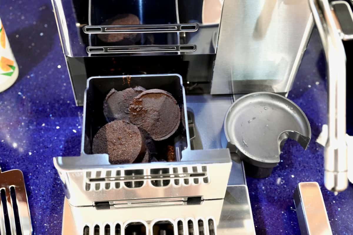 Top-down close-up view of the pulled-out waste bin filled with discarded espresso coffee pucks inside the Ninja AutoBarista Pro.