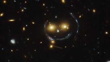 Captured by the Hubble Space Telescope, galaxy cluster SDSS J1038+4849 creates a giant cosmic smiley face through the physics of gravitational lensing. ©Image Credit: NASA