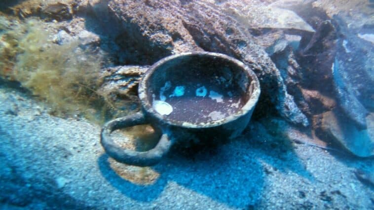 An ancient Greek drinking cup lies in situ on the seabed alongside preserved wooden hull timbers at the 2,300-year-old Gnjilna Bay shipwreck off the island of Vis, Croatia | ©Image Credit: Jurica Bezak / Croatian Conservation Institute (HRZ)